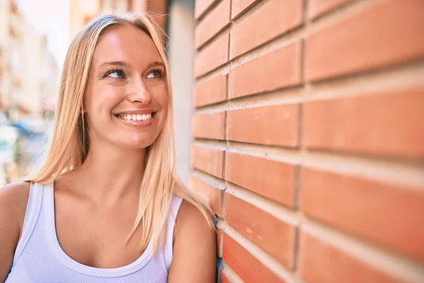 Genç Sarışın Kız Mutlu Bir Şekilde Gülümsüyor Şehrin Duvarına Yaslanıyor — Stok fotoğraf