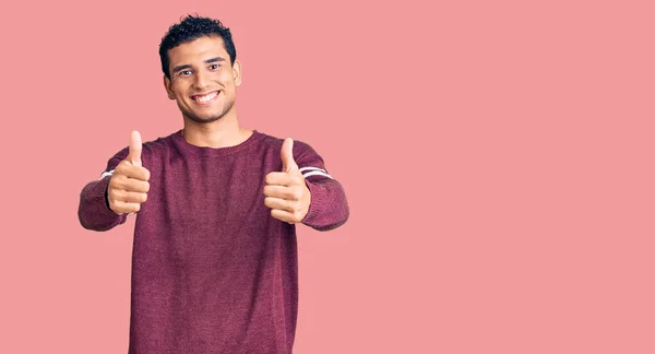 ヒスパニック系ハンサムな若い男は 手で積極的なジェスチャーを行うことを承認カジュアル服を着て 親指を笑顔と成功のために幸せ 勝者のジェスチャー — ストック写真