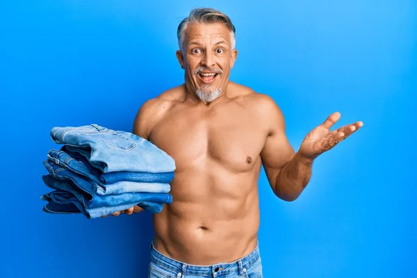 Hombre Pelo Gris Mediana Edad Sin Camisa Sosteniendo Pila Vaqueros — Foto de Stock