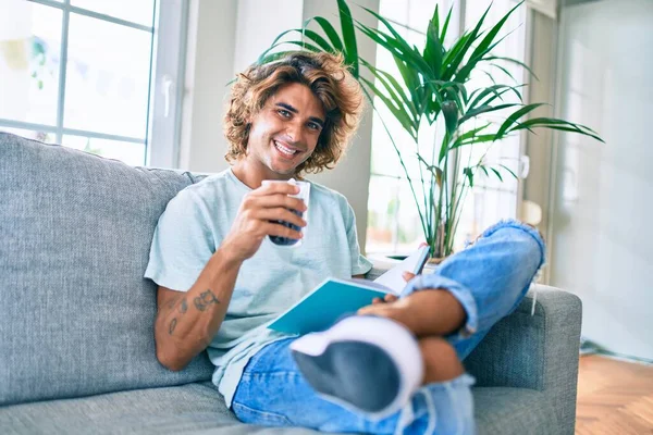 Joven Hispano Sonriendo Feliz Leyendo Libro Tomando Café Casa —  Fotos de Stock