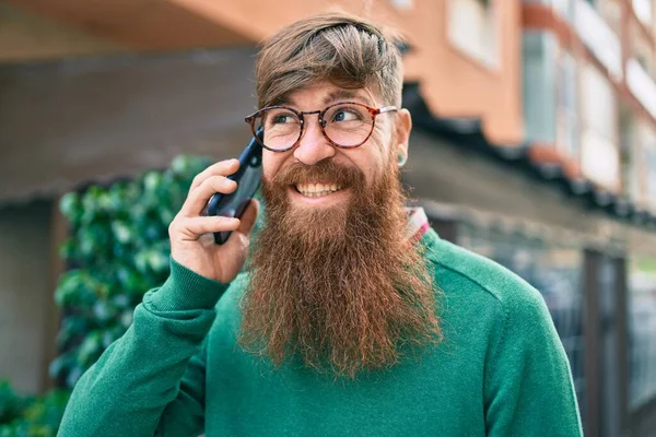 Young irish man with redhead beard smiling happy and talking on the smartphone at the city.