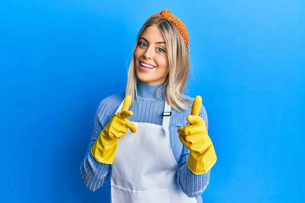 Beautiful Blonde Woman Wearing Cleaner Apron Gloves Pointing Fingers Camera — Stock Photo, Image