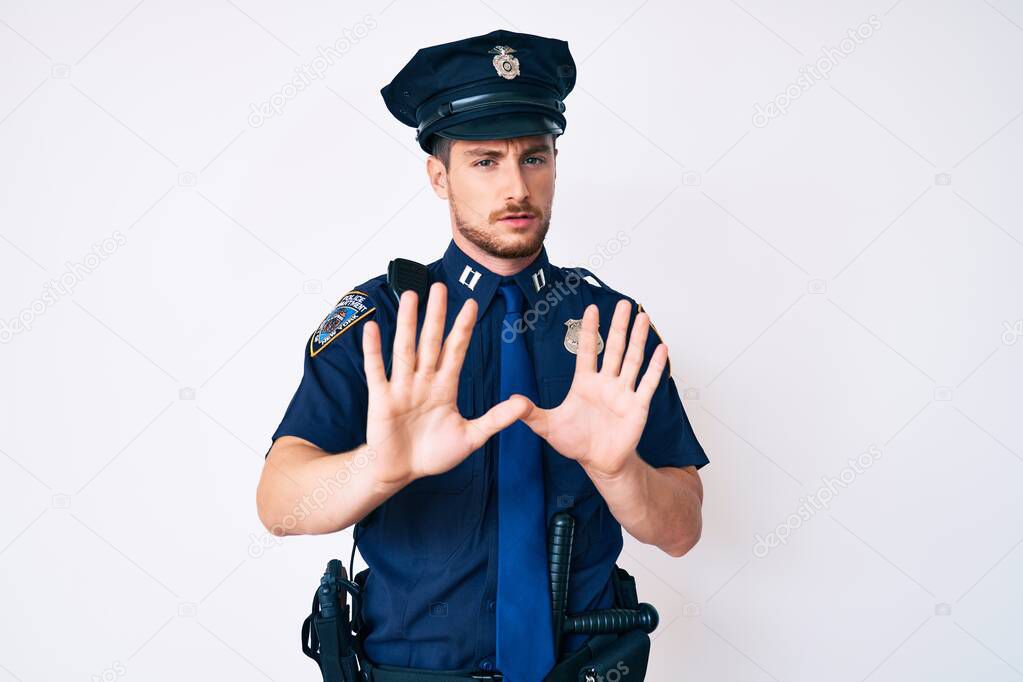 Young caucasian man wearing police uniform moving away hands palms showing refusal and denial with afraid and disgusting expression. stop and forbidden. 