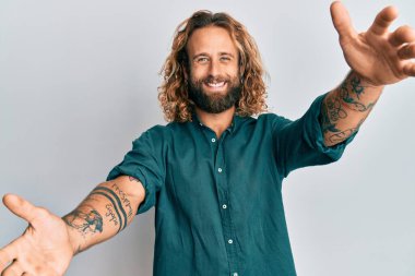 Sakallı, uzun saçlı, sıradan kıyafetler giyen yakışıklı bir adam kameraya sarılıp gülümsüyor. Mutluluğu kucaklayan neşeli bir ifade.. 