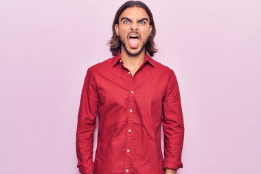 İş kıyafetleri giymiş genç yakışıklı bir adam komik bir ifadeyle dilini dışarı çıkarıyor. duygu kavramı. 