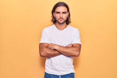 Gündelik kıyafetler giyen, kuşkucu ve gergin genç yakışıklı bir adam. Yüzünde çapraz kollarla onaylamayan bir ifade var. negatif kişi. 