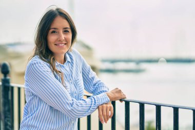 Genç İspanyol kadın gülümsüyor mutlu bir şekilde kentteki korkuluklara yaslanıyor..