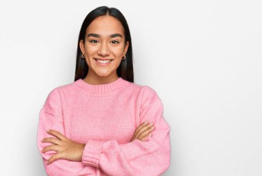 Sıradan bir kazak giyen genç Asyalı kadın kollarını kavuşturup kameraya bakarken gülümsüyor. pozitif kişi. 