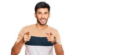 Gündelik giysiler giymiş genç yakışıklı adam mutlu ve komik yüzüyle kamerayı işaret ediyor. iyi enerji ve titreşimler. 