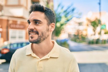 Genç İspanyol adam gülümseyerek şehirde mutlu bir şekilde yürüyor..