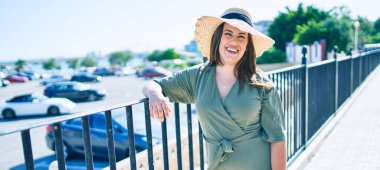 Genç İspanyol kadın tatilde mutlu bir şekilde gülümsüyor. Kentin caddesinde korkuluğa yaslanıyor.