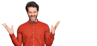 Gündelik kıyafetler giyen genç İspanyol adam başarı için deli ve çılgınlığı kutluyor kollarını kaldırmış ve gözlerini kapatmış heyecanla bağırıyor. Kazanan konsept 