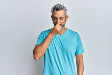 Orta yaşlı, gri saçlı, günlük kıyafetler giyen, pis ve iğrenç bir koku alan, nefesini burnunda tutan bir adam. Kötü kokuyor. 