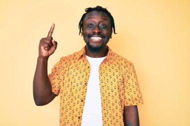 Saçları örgülü, sıradan giyinmiş, başarılı bir fikri işaret eden Afro-Amerikalı genç bir adam. Heyecanlı ve mutlu. Bir numara.. 