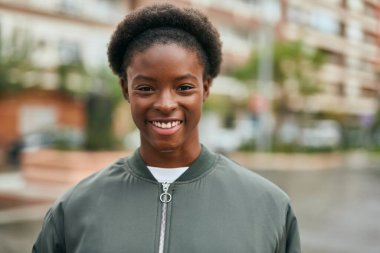 Genç Afrikalı Amerikalı kız gülümseyerek şehirde mutlu mesut duruyor..