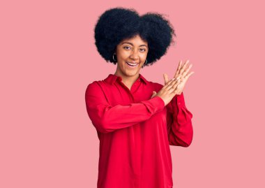 Genç Afro-Amerikan kızı günlük giysiler içinde alkışlıyor ve mutlu ve neşeli alkışlıyor, gururla gülümsüyor. 