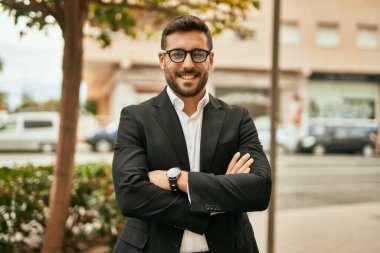 Kollarını kavuşturmuş genç İspanyol işadamı şehirde mutlu bir şekilde gülümsüyor..