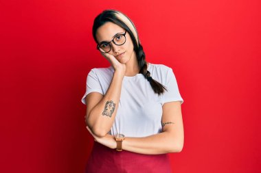 Profesyonel garson önlüğü giyen genç İspanyol kadın kollarını kavuşturarak depresyon sorunlarından sıkılmış ve yorgun görünüyor.. 