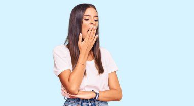 Günlük beyaz tişört giyen genç İspanyol kadın ağzıyla ağzını kapatmaktan sıkılmış. Huzursuz ve uykulu.. 