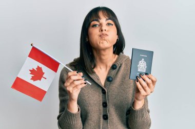 Genç İspanyol kadın elinde Kanada bayrağı ve komik suratlı yanakları şişiren pasaport taşıyor. Ağzı havayla şişer, havayı yakalar.. 