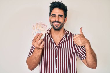 Birleşik Krallık 'ta sakallı yakışıklı bir İspanyol. Gülümsüyor, mutlu ve pozitif. Başparmağıyla mükemmel ve onay işareti yapıyor. 