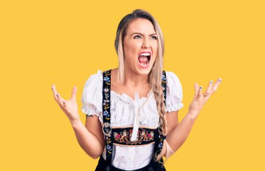 Oktoberfest elbisesi giyen genç, güzel sarışın kadın deli gibi bağırıyor ve agresif bir ifade ve kollarla bağırıyor. hüsran kavramı. 