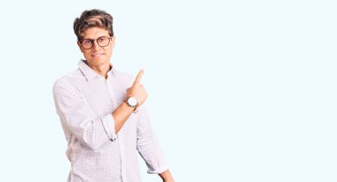 İş kıyafetleri ve gözlük takan genç yakışıklı adam el ile işaret ederek reklamını yapıyor, ciddi ve sakin bir yüz ifadesi. 