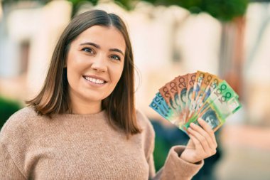 Genç İspanyol kadın gülümseyerek Avustralya dolarlarını şehirde tutuyor..