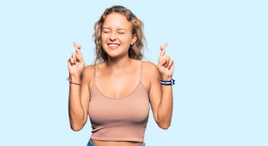 Güzel, beyaz bir kadın günlük kıyafetler giyip umut ve gözlerin kapalı bir şekilde el işareti yaparak gülümsedi. Şans ve batıl inançlar. 