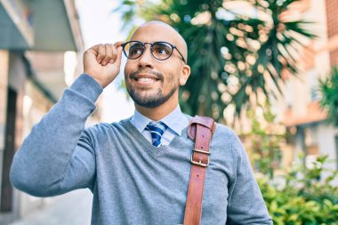 Genç Afrikalı Amerikalı iş adamı gülümseyerek şehirde mutlu bir şekilde yürüyor..