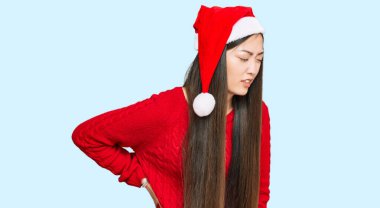 Genç Çinli kadın Noel şapkası takıyor sırt ağrısı çekiyor, elleriyle dokunuyor, kas ağrısı çekiyor. 