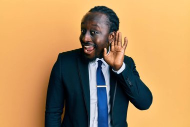 Yakışıklı, takım elbiseli ve kravatlı genç bir adam. Kulağından kulağa gülümseyen ve dedikoduları ve dedikoduları dinleyen. Sağırlık kavramı. 