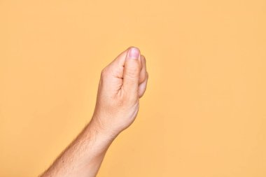 İzole edilmiş sarı arka planda parmaklarını gösteren beyaz bir adamın eli. Parmak, iş ve reklamla boş bir alan tutuyor.