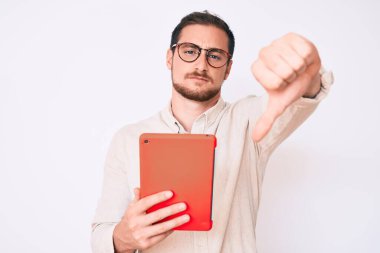 Genç yakışıklı bir adam kızgın yüzlü dokunmatik ped kullanıyor, negatif işaret baş parmakları aşağıda, reddedilme konsepti 