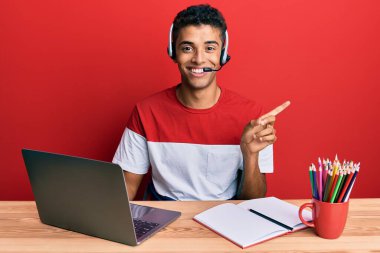 Genç, yakışıklı, afro-amerikan bir adam ofiste çalışıyor operatör kulaklığı takıyor, gülümsüyor, mutlu bir şekilde elini ve parmağını yana uzatıyordu. 