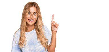 Günlük kravat boyası tişörtü giyen güzel sarışın bir kadın başarılı bir fikri işaret ediyor. Heyecanlı ve mutlu. Bir numara.. 