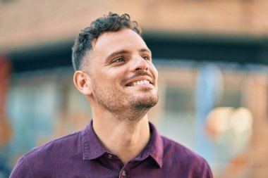 Genç İspanyol adam gülümseyerek şehirde mutlu mesut dikiliyor..