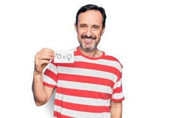 Orta yaşlı bir adam, elinde eşit haklara sahip kadın ve erkek kavramının olduğu bir kağıt tutarak olumlu ve mutlu görünmesini ve kendine güvenen bir gülümsemeyle dişlerini göstermesini istiyor.