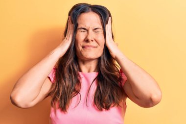 Sarı arka planda duran pembe tişörtlü, güzel esmer kadın. Başı ağrıyor, çünkü stres var. Migren ağrısı..