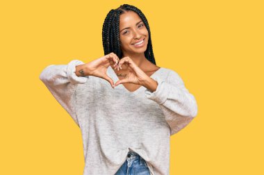 Güzel İspanyol kadın, gündelik kıyafetler giyip, aşık gülümsüyor, elleriyle kalp sembolü yapıyor. romantik kavram. 