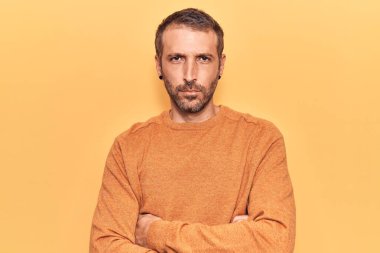 Gündelik kıyafetler giyen, kuşkucu ve gergin genç yakışıklı bir adam. Yüzünde çapraz kollarla onaylamayan bir ifade var. negatif kişi. 