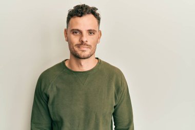 Günlük kıyafetler giyen genç İspanyol adam yüzünde ciddi bir ifadeyle rahatlamış. Basit ve doğal bir şekilde kameraya bakıyorsun.. 