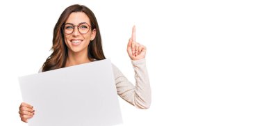 Boş afiş tutan genç esmer kadın bir fikre ya da mutlu yüzle işaret eden bir soruya şaşırdı. 