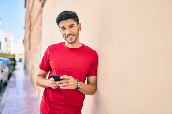 若いラテン語の男笑顔幸せな使用してスマートフォンで市 — ストック写真