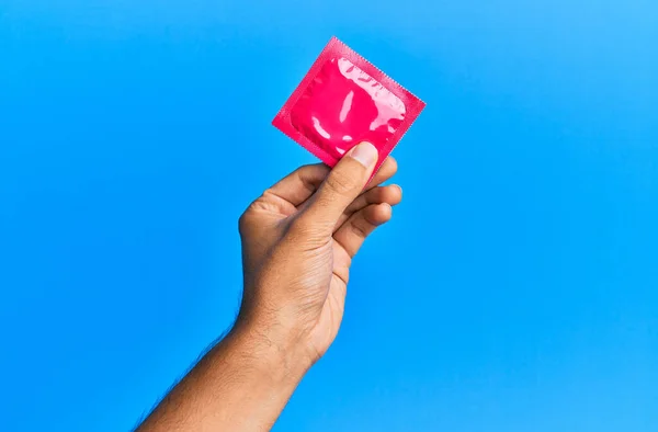 Young Hispanic Hand Holding Condom Isolated Blue Background — Stock Photo, Image