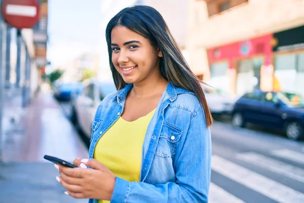 若いラテン語の女性笑顔幸せな使用してスマートフォンで市内 — ストック写真
