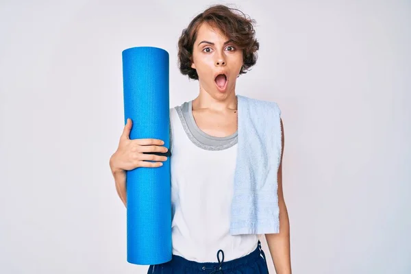 Young Hispanic Woman Holding Yoga Mat Scared Amazed Open Mouth — Fotografia de Stock