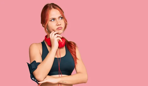 Young Redhead Woman Wearing Gym Clothes Using Headphones Serious Face — Stock fotografie