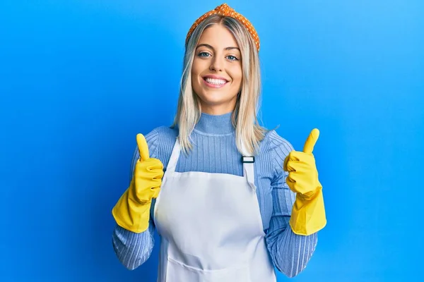 Schöne Blonde Frau Trägt Putzschürze Und Handschuhe Erfolgszeichen Tun Positive — Stockfoto