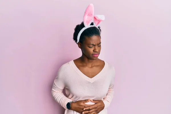 年轻的非洲裔美国女孩 手放在肚子上 头戴可爱的复活节兔子耳朵 因为消化不良 痛苦不堪 疼痛的概念 — 图库照片